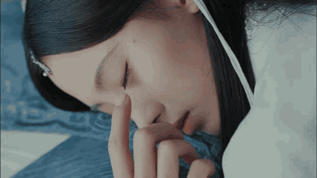 a close up of a woman laying down with her hand on her face