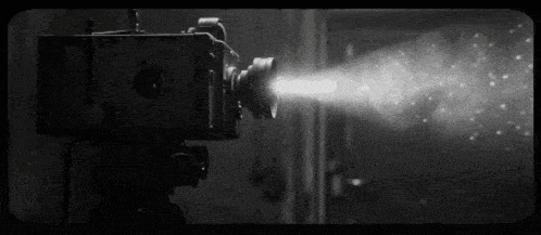 a black and white photo of an old movie camera shooting a film .