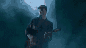 a man is playing a guitar and singing into a microphone on stage .