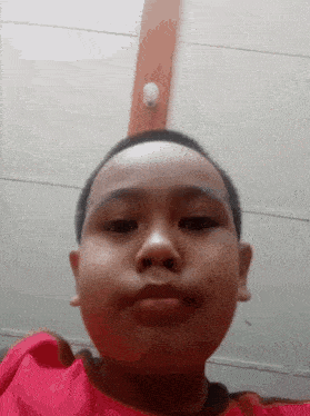 a young boy is taking a selfie in front of a wall with a light on it