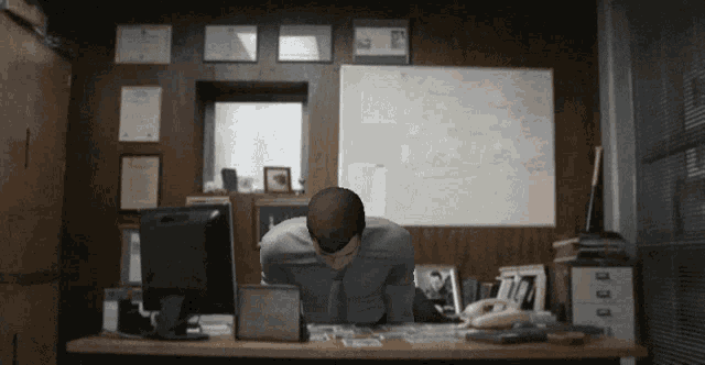 a man sits at a desk with his head down in front of a computer