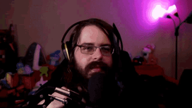 a man with glasses and a beard is wearing headphones and holding a microphone