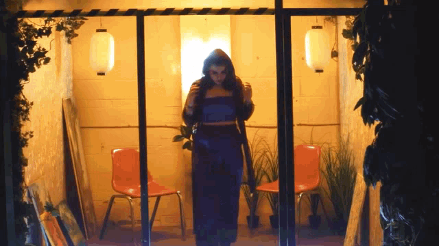 a woman in a purple dress stands in a doorway