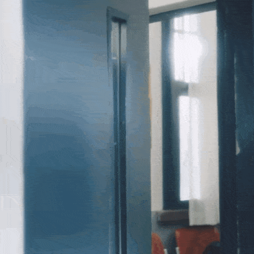 a blue door is open to a window in a room