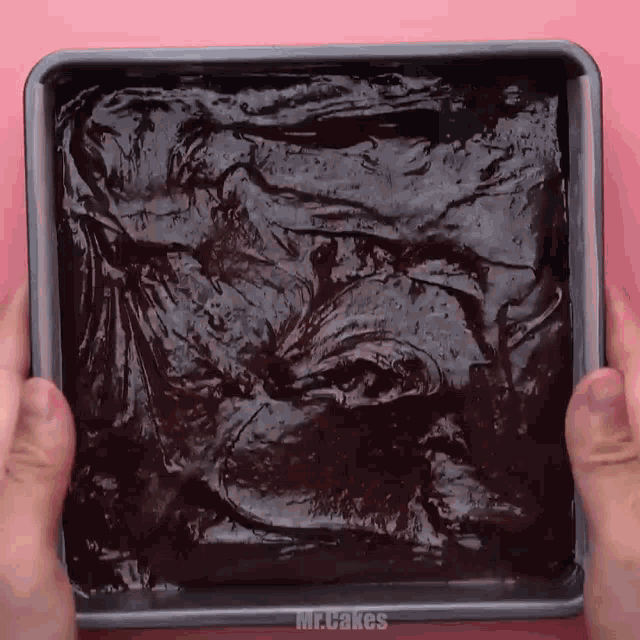a person is holding a pan of brownies that says mr cakes on it