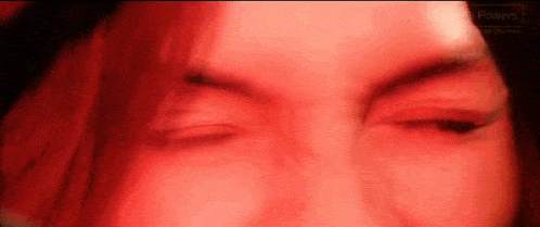 a close up of a woman 's face with a red light behind her .
