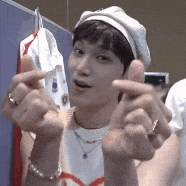 a young man is making a heart shape with his fingers .