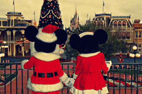 mickey mouse and minnie mouse looking at a christmas tree at disneyland