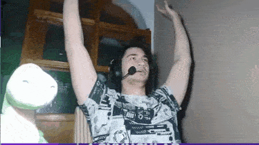 a man wearing headphones and a microphone is raising his hands in the air .
