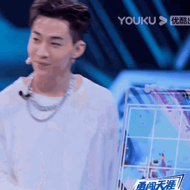 a man in a white shirt stands in front of a screen that says youku