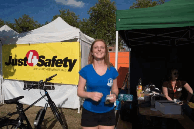 a woman stands in front of a tent that says just 4 safety