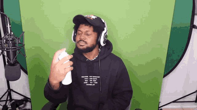 a man wearing headphones and a black hoodie spraying something