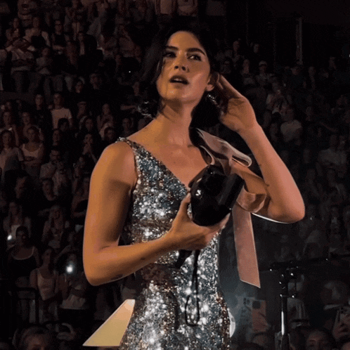 a woman in a sequined dress holds a camera in her hand