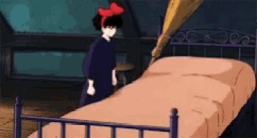 a girl with a red bow on her head is standing next to a bed in a room .