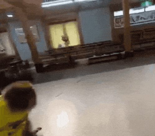 a person in a yellow jacket is standing in a room with a lot of empty seats .
