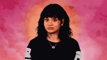 a girl with a tattoo on her face is wearing a black shirt with the letter l on it
