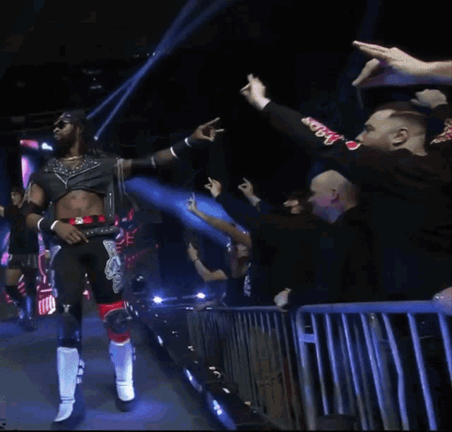 a wrestler wearing a crop top with the number 3 on it stands in front of a crowd