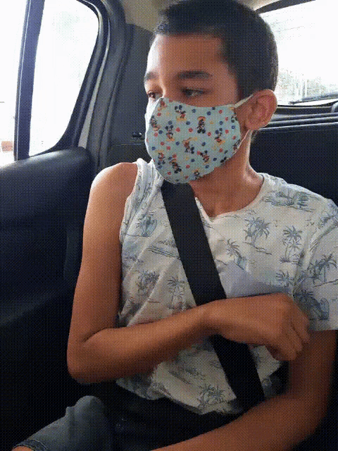 a young boy wearing a face mask is sitting in a car