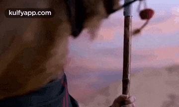 a man is holding a wooden stick in the desert .