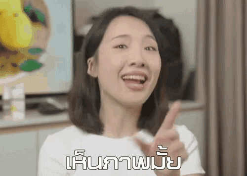 a woman in a white shirt is making a funny face and pointing up