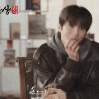 a man sitting at a table with chinese writing on the wall