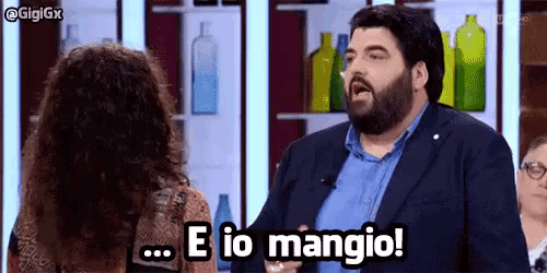 a man with a beard is talking to a woman on a television show and says e io mangio !