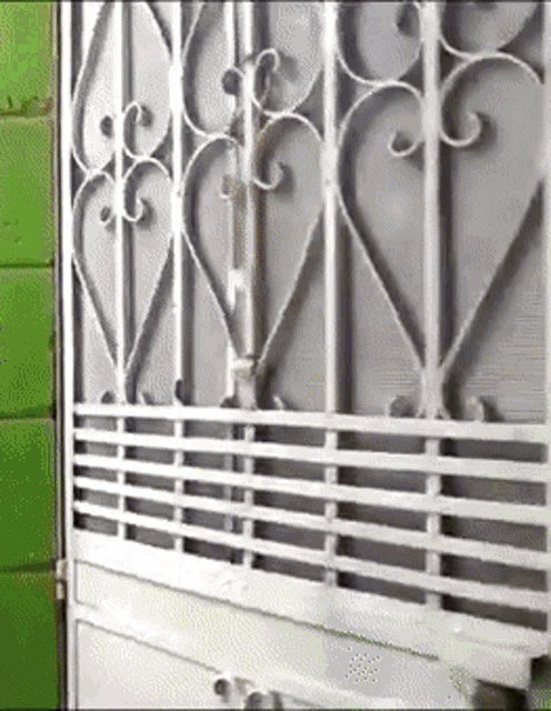 a wrought iron gate with hearts on it is against a green wall