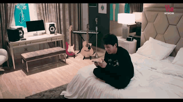 a man is sitting on a bed in a room with a we network logo