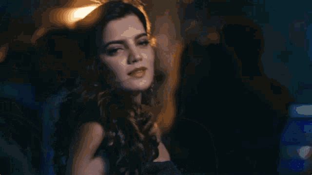 a woman in a blue dress looks at the camera