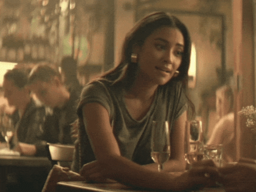 a woman sitting at a table holding a glass of wine