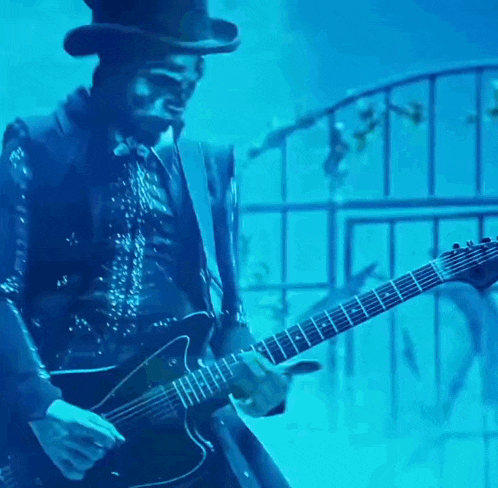 a man in a top hat is playing a guitar in a dark room