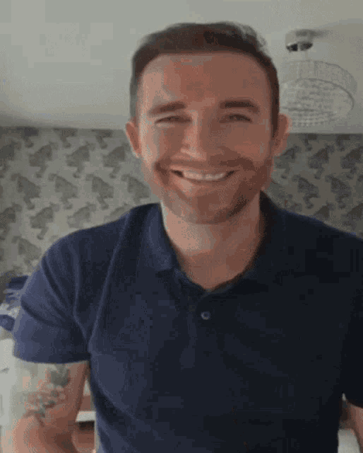 a man with a beard wearing a blue polo shirt is smiling