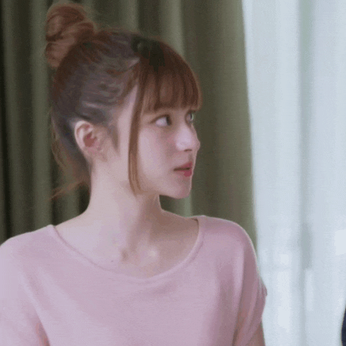 a woman with her hair in a bun is wearing a pink top