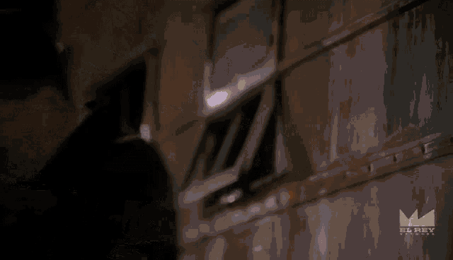 a man in a dark room with a el rey logo on the bottom right
