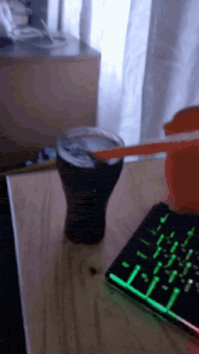 a cup of coke sits on a table next to a keyboard