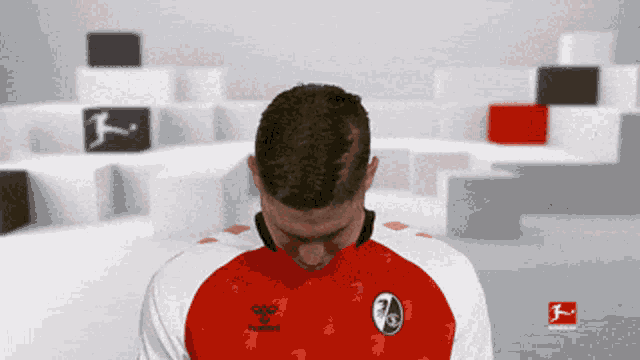 a man wearing a red and white hummel shirt looks down
