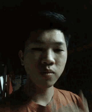a young man in an orange shirt is making a face