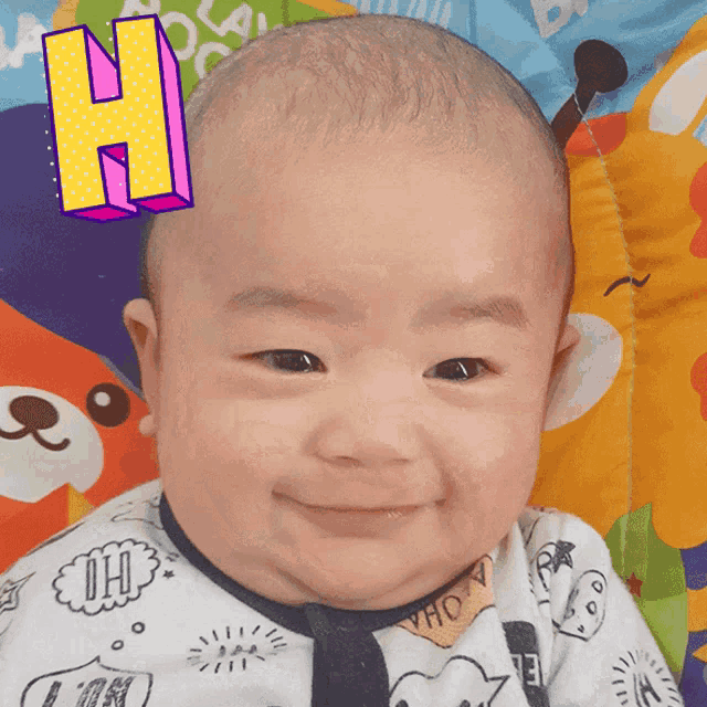 a baby is smiling with the letter h on his head