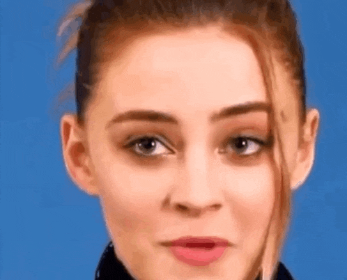 a close up of a woman 's face making a funny face against a blue background .