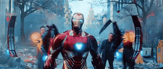 iron man is standing in the middle of a destroyed city with a group of people .