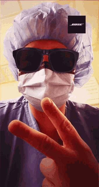 a person wearing a surgical mask and sunglasses with a bose logo