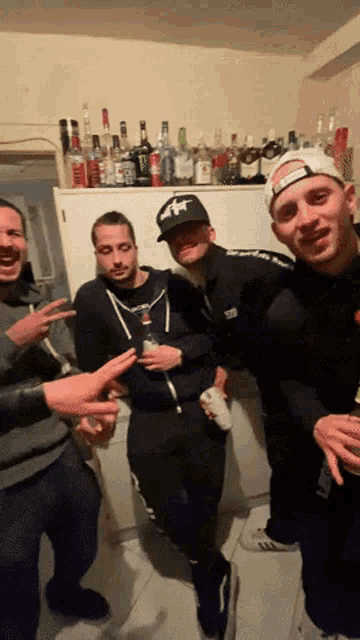 a group of men are posing for a picture in front of a refrigerator full of liquor