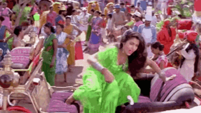 a woman in a green dress is sitting on a chair in front of a crowd .