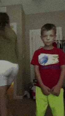 a boy in a red shirt stands in front of a woman in a green shirt