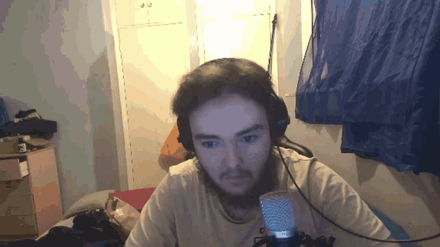 a man with a beard is wearing headphones and a microphone in a room
