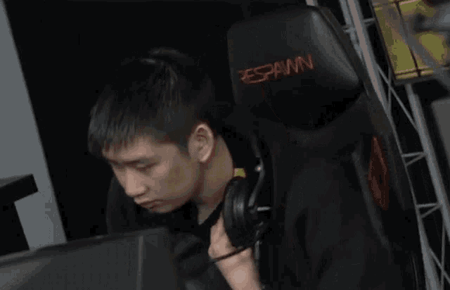 a man wearing headphones sits in a chair that says spam on it