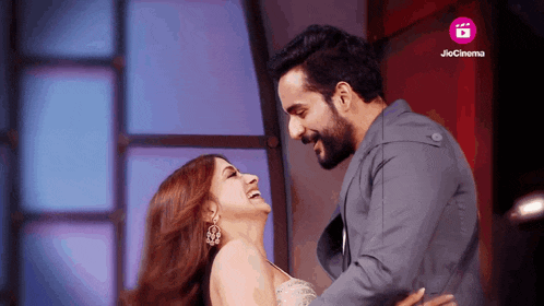 a man and a woman are hugging each other with a jio cinema logo in the background