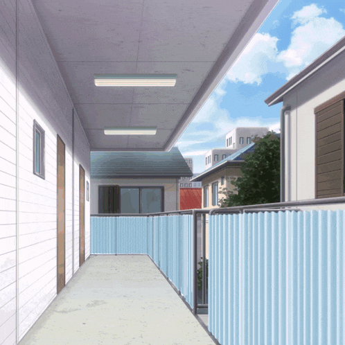 a hallway with a blue fence leading to a balcony in a residential area