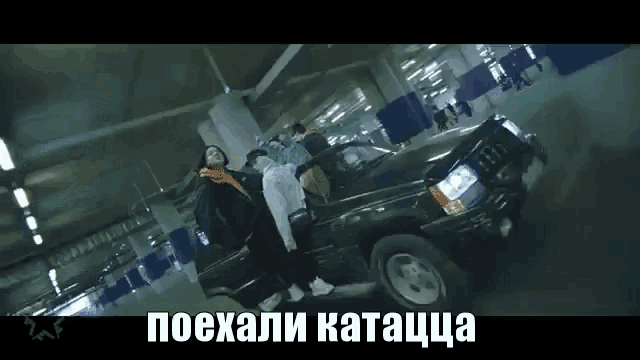 a group of people standing next to a car in a parking garage with russian writing