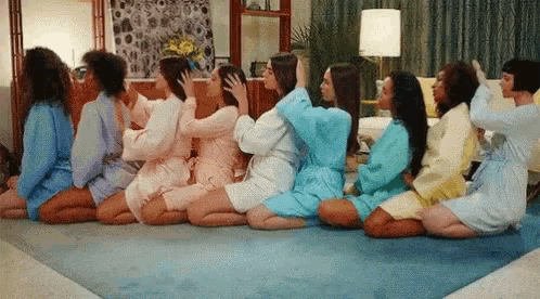 a group of women are sitting on the floor in a row .